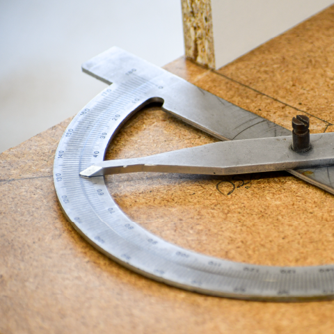Metallisches Winkelmessgerät auf einer Holzwerkplatte.