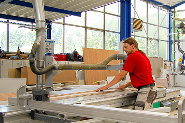 Mitarbeiter arbeitet an einer Formatkreissäge in der Clasen & Co Produktionshalle.