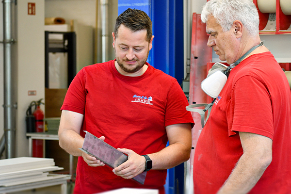 Zwei Mitarbeiter besprechen ein Werkstück in einer Produktionshalle.