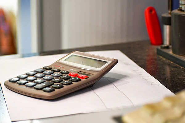 Taschenrechner liegt auf einem Blatt Papier auf einer Werkbank.